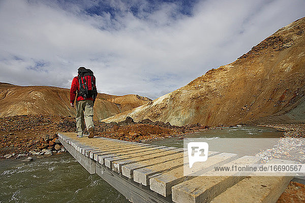 Wanderer beim Überqueren einer Holzbrücke im isländischen Hochland