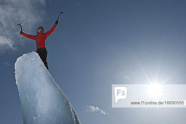 Frau klettert auf einen Eisberg in der Lagune des Fjallsjoull-Gletschers