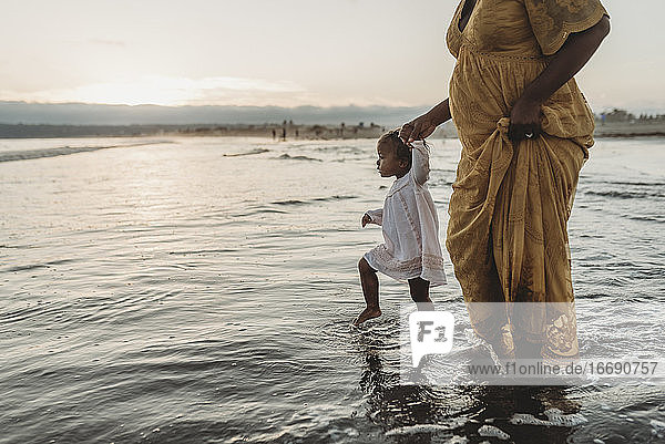 Junge Tochter und schwangere Mutter gehen ins Meer