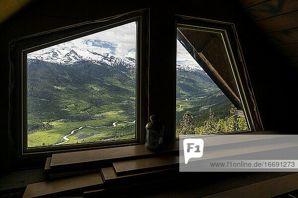 Berge und grünes Tal hinter dem Hüttenfenster