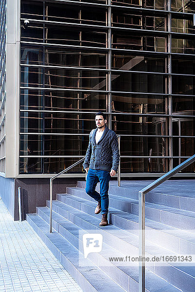 Junger bärtiger Mann geht die Treppe eines Bürogebäudes hinunter