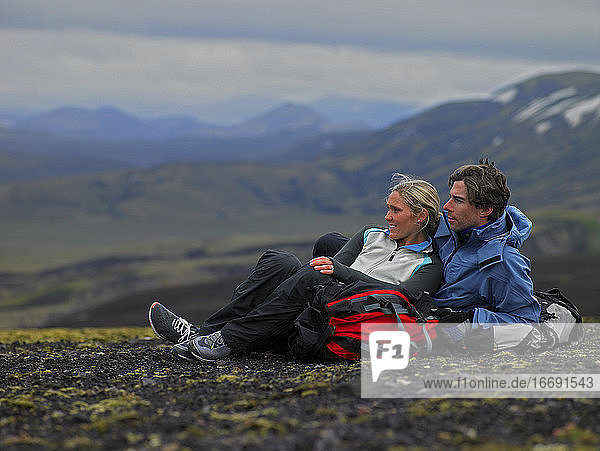 Wanderndes Paar entspannt sich am Berghang in Island