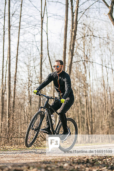Männlicher Mountainbiker fährt durch den Wald