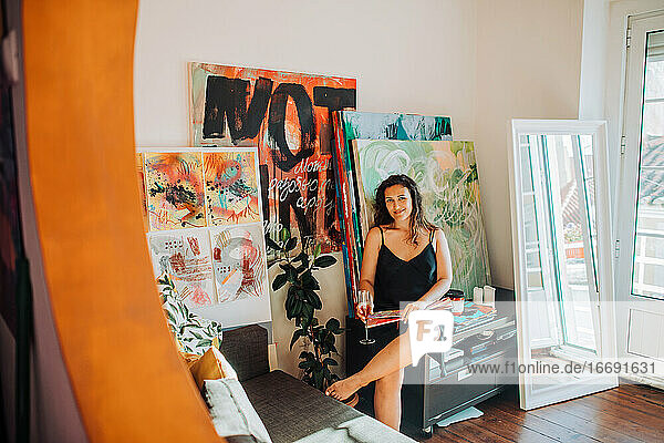 Künstlerin in ihrem Atelier  umgeben von Leinwand und Gemälden