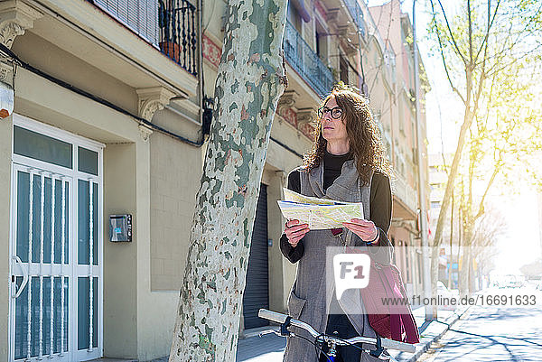 Touristin in der Stadt mit Fahrrad bei der Überprüfung des Stadtplans