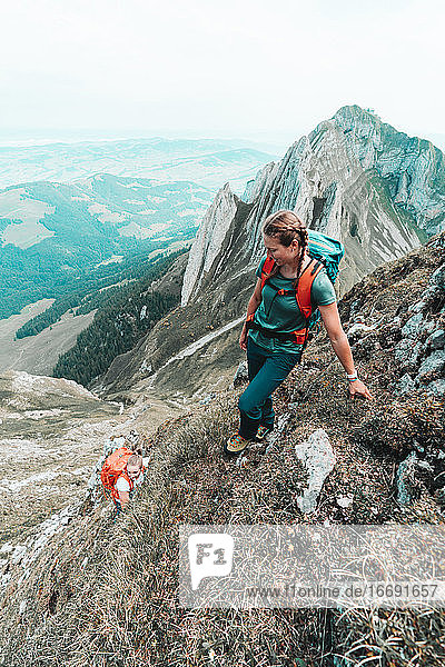 Zwei aktive Bergsteigerinnen beim Aufstieg auf einen steilen Grasberg in der CH