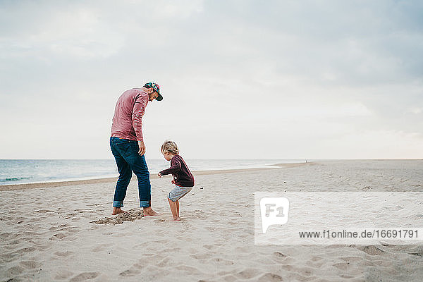 Vater und Kind spielen am Strand an einem bewölkten Tag