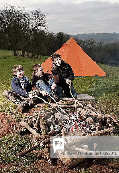 drei Jungen sitzen am Lagerfeuer in Südwales