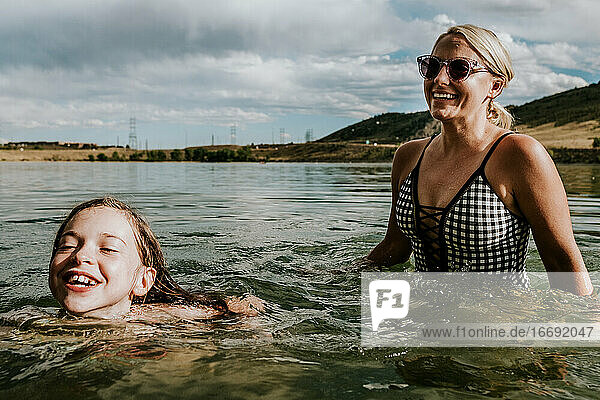 Mom and daughter happily playing in a lake on a summer day