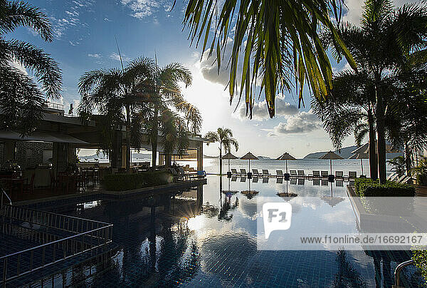 Liegestühle und Sonnenschirm am Pool einer Ferienanlage in Phuket