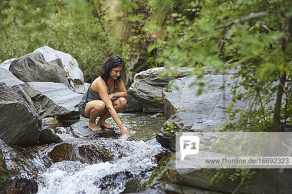 Junge Frau in einem Fluss. Erfrischt sich an einem heißen Sommernachmittag.