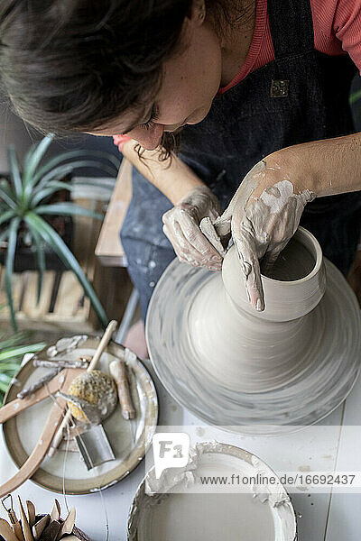 Junge Frau bearbeitet Ton in einem Keramikstudio von oben