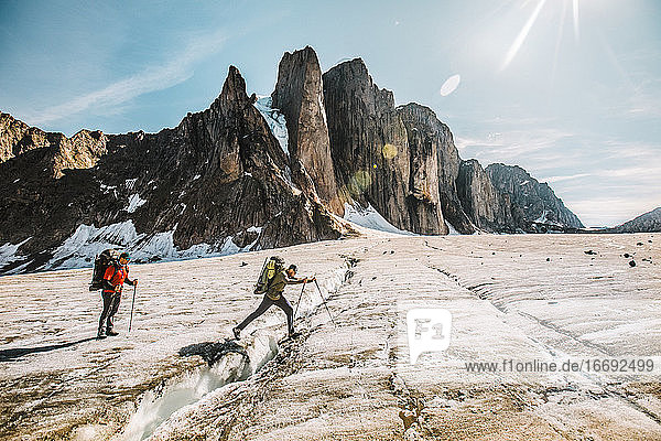Mounatineer crosses a glacial crevasse on a sunny day  Baffin Island.