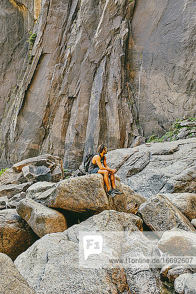 Junger Mann ruht sich auf einem Felsen aus und beobachtet die Yosemite Falls.