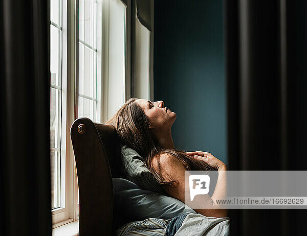 Spiegelreflexion einer Frau  die in einem dunklen Schlafzimmer auf einem Bett liegt.