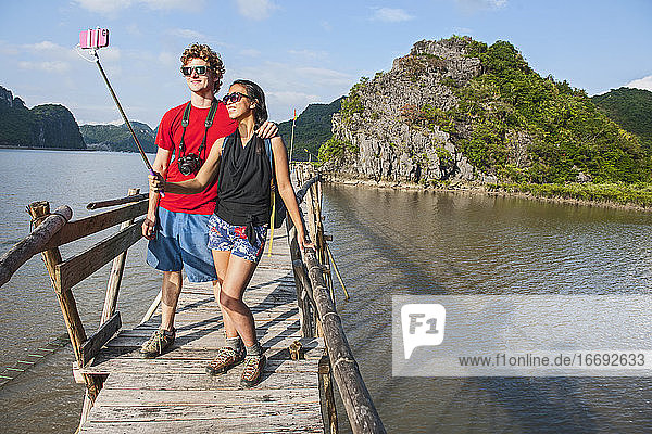 young couple taking selfie on boardwalk in Vietnam's Halong Bay