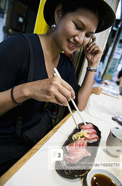 Frau genießt frisches Sushi auf einem Straßenmarkt in Tokio