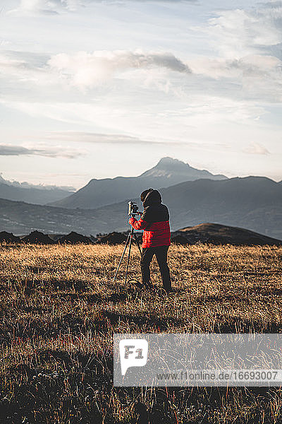 Fotograf beim Fotografieren in den Bergen mit Bergen im Hintergrund