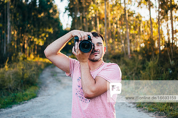 Portrait of young man taking photo with camera