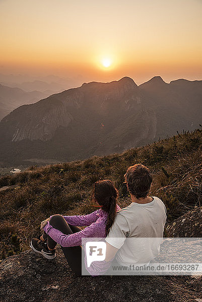 Schöne Aussicht auf ein wanderndes Paar  das den Sonnenuntergang vom Berggipfel aus genießt