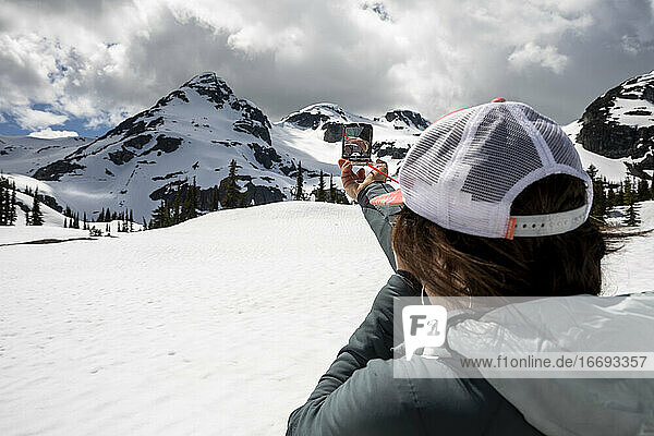 Anonyme Frau benutzt Kompass in verschneiten Bergen