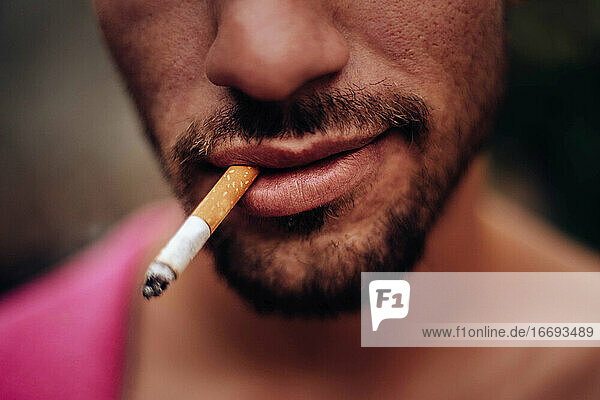 Mund eines jungen Mannes  der lächelnd eine Zigarette raucht