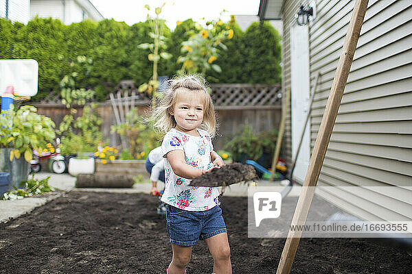 Ein junges Mädchen hilft bei einem Landschaftsbauprojekt in ihrem Garten.