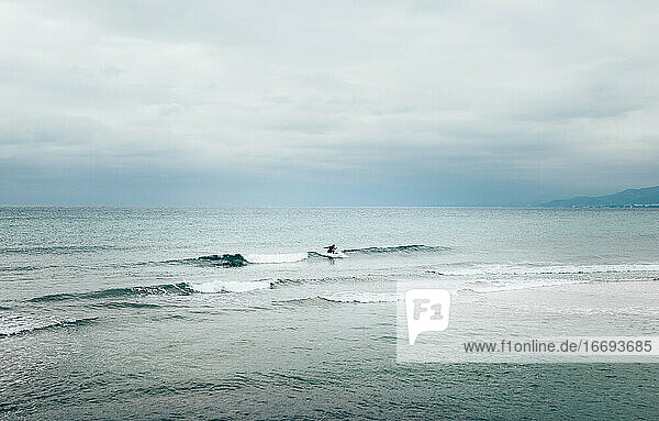 Silhouette in der Mitte eines Mannes Surfen im Meer in der Nähe der Küste