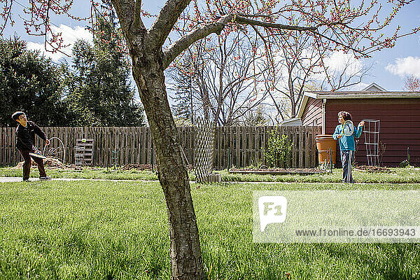 Ein Vater und sein Sohn spielen Tennis über einen Holzzaun in einem Garten im Frühling