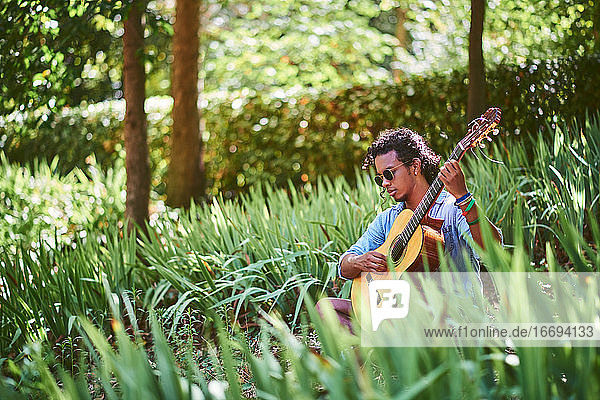 Musician practicing with the guitar in the field.
