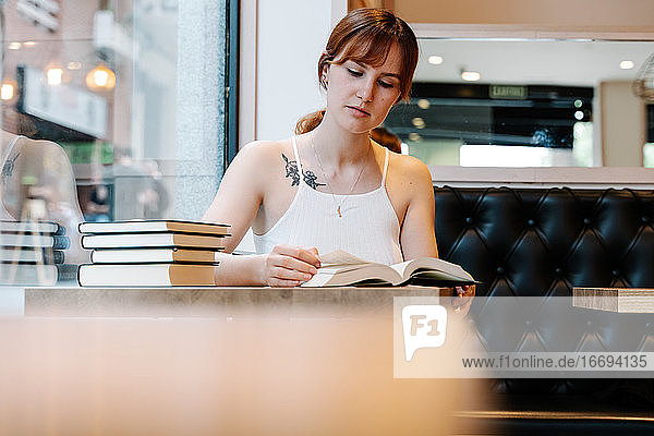 Junge Frau liest Bücher in einem Café