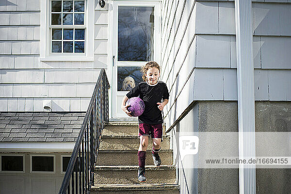 Mädchen läuft mit Fußball die Treppe hinunter