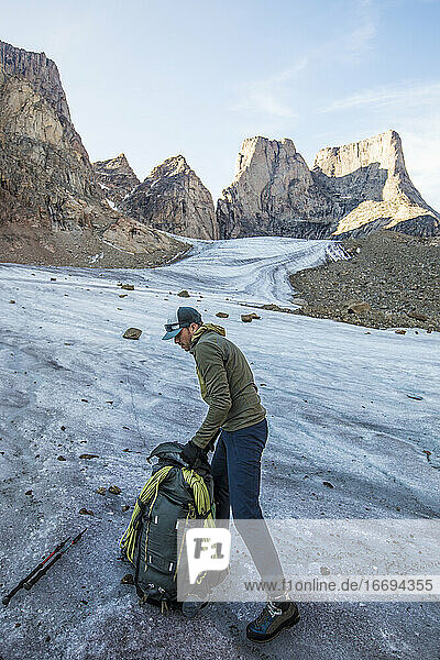 Rucksacktourist packt seine Tasche auf dem Gletscher unterhalb des Mount Asgard.