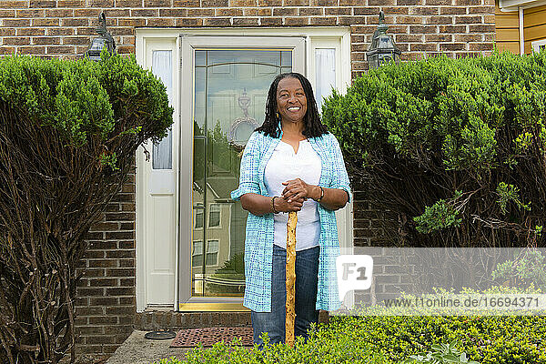 Porträt einer afroamerikanischen Frau  die vor ihrem Haus steht