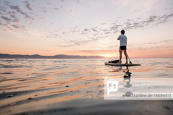Concept  peace  calm and freedom. Man paddling upright on the pa