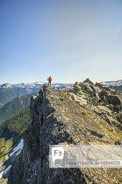 Bergsteiger steht auf dem Gipfel eines felsigen Berges  B.C. Kanada