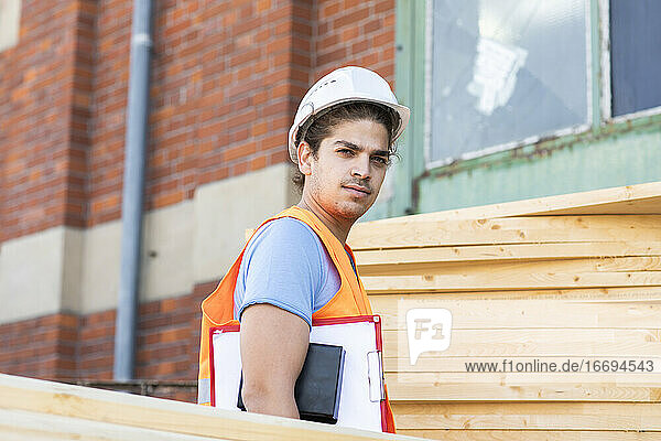 junger Bauingenieur mit Helm bei der Arbeit im Freien