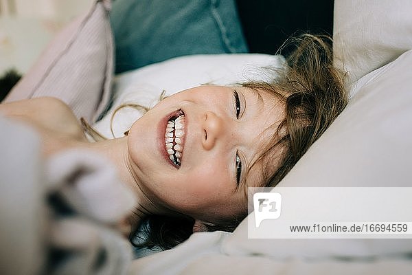 candid close up portrait of girl laying down laughing