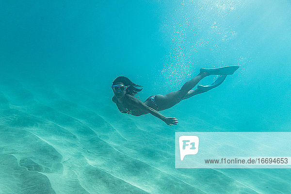Freitaucherin schwimmt in der Nähe des sandigen Bodens des Ozeans von Oahu