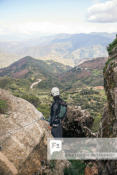 Konzept: Abenteuer. Bergsteiger Mann mit Helm und Gurtzeug. Blick von hinten auf die andalusische Naturlandschaft. Klettern auf den Gipfel des Berges. Via ferrata auf Felsen.