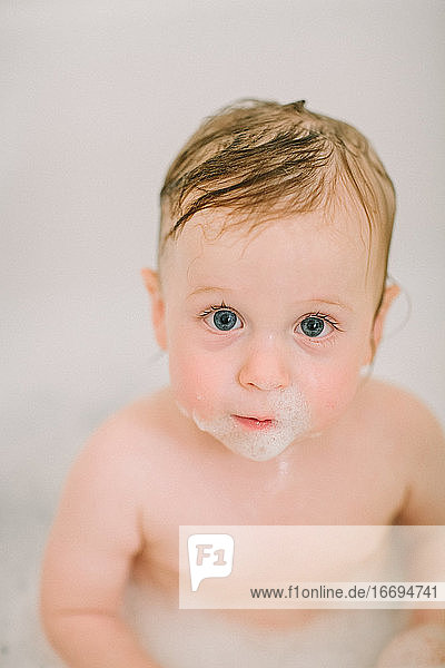 Closeup of baby in the bathtube with bubbles on face