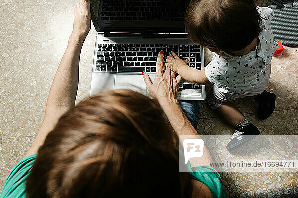 Remote working mother with kid using laptop