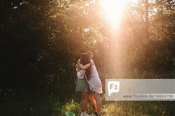 Glückliche Freundinnen umarmen sich im Sommer im Wald
