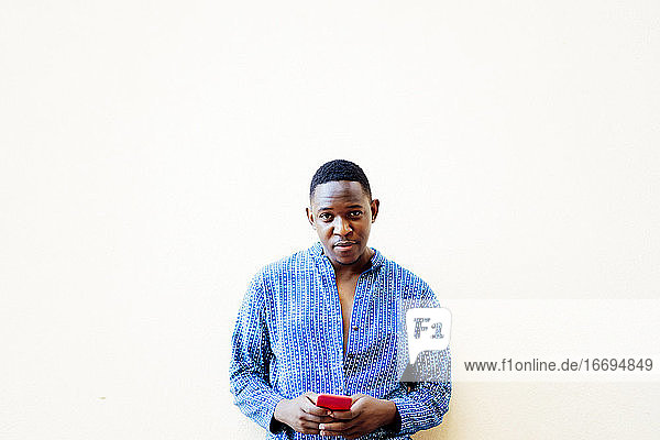 junger afrikanischer Mann benutzt sein rotes Smartphone