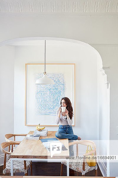 Portrait woman drinking coffee in white  bright kitchen