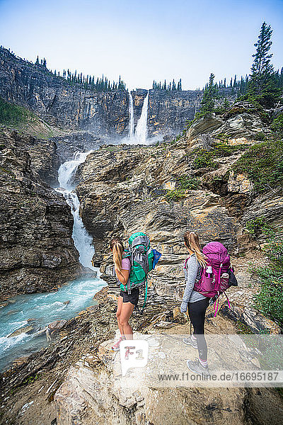 Zwei Wanderer bewundern den Wasserfall Twin Falls im Yoho National Park