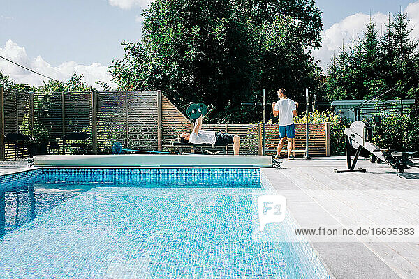 zwei Männer trainieren zusammen am Pool im heimischen Fitnessstudio