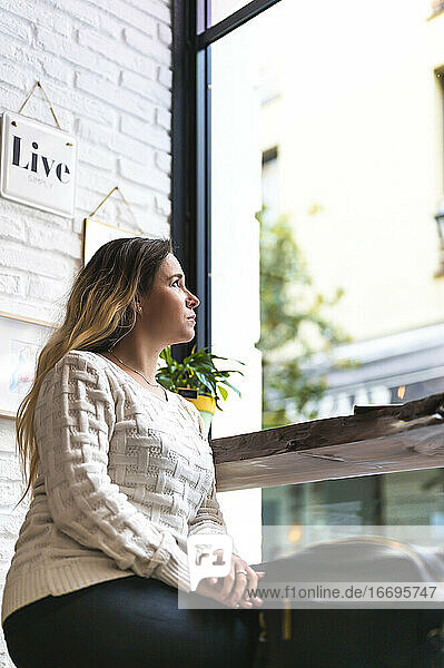 Frau schaut in einem Café zum Fenster hinauf