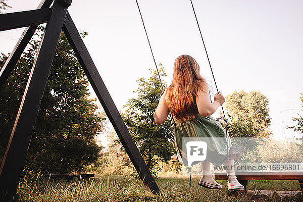 Teenage girl swinging in park during summer