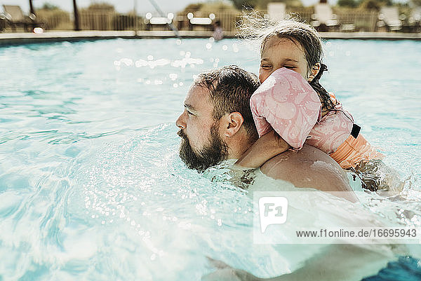Vater und Tochter schwimmen zusammen in einem Pool im Urlaub in Kalifornien